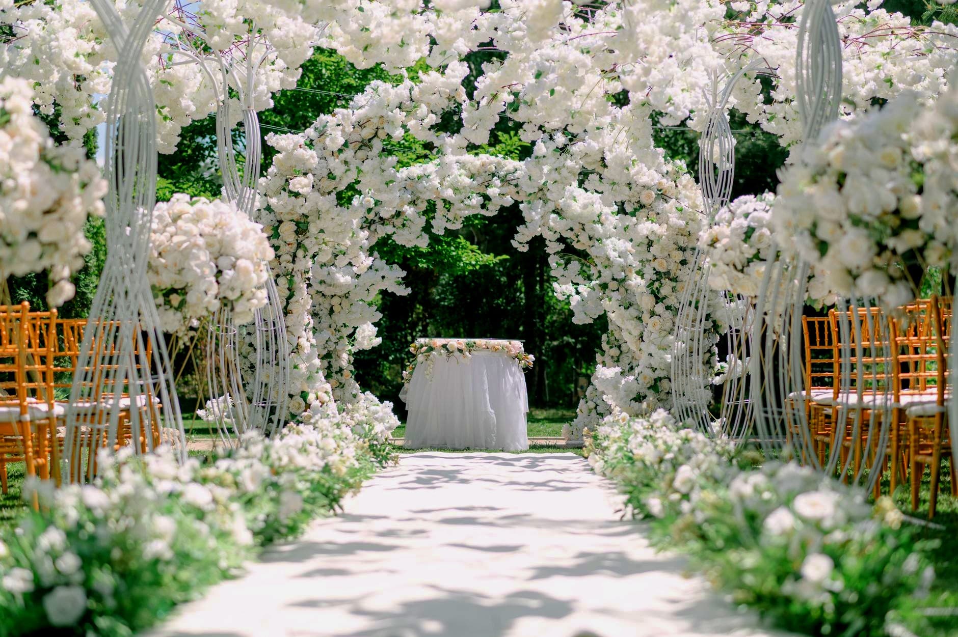 An outdoor ceremony aisle under white florals